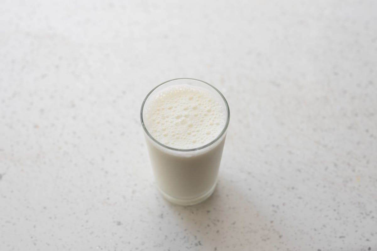 a glass of fresh milk on a white surface