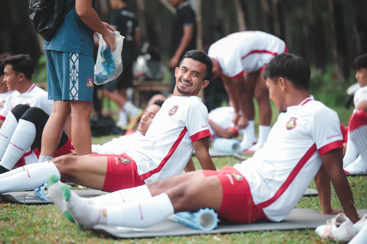 a group of men sitting on the grass with their legs up