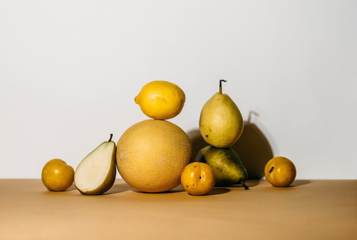 a group of yellow fruits and green pear on brown surface