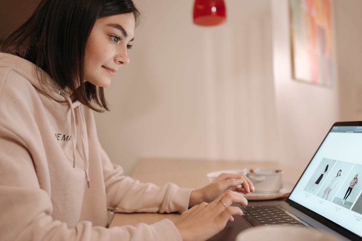 a woman in pink hoodie browsing on laptop
