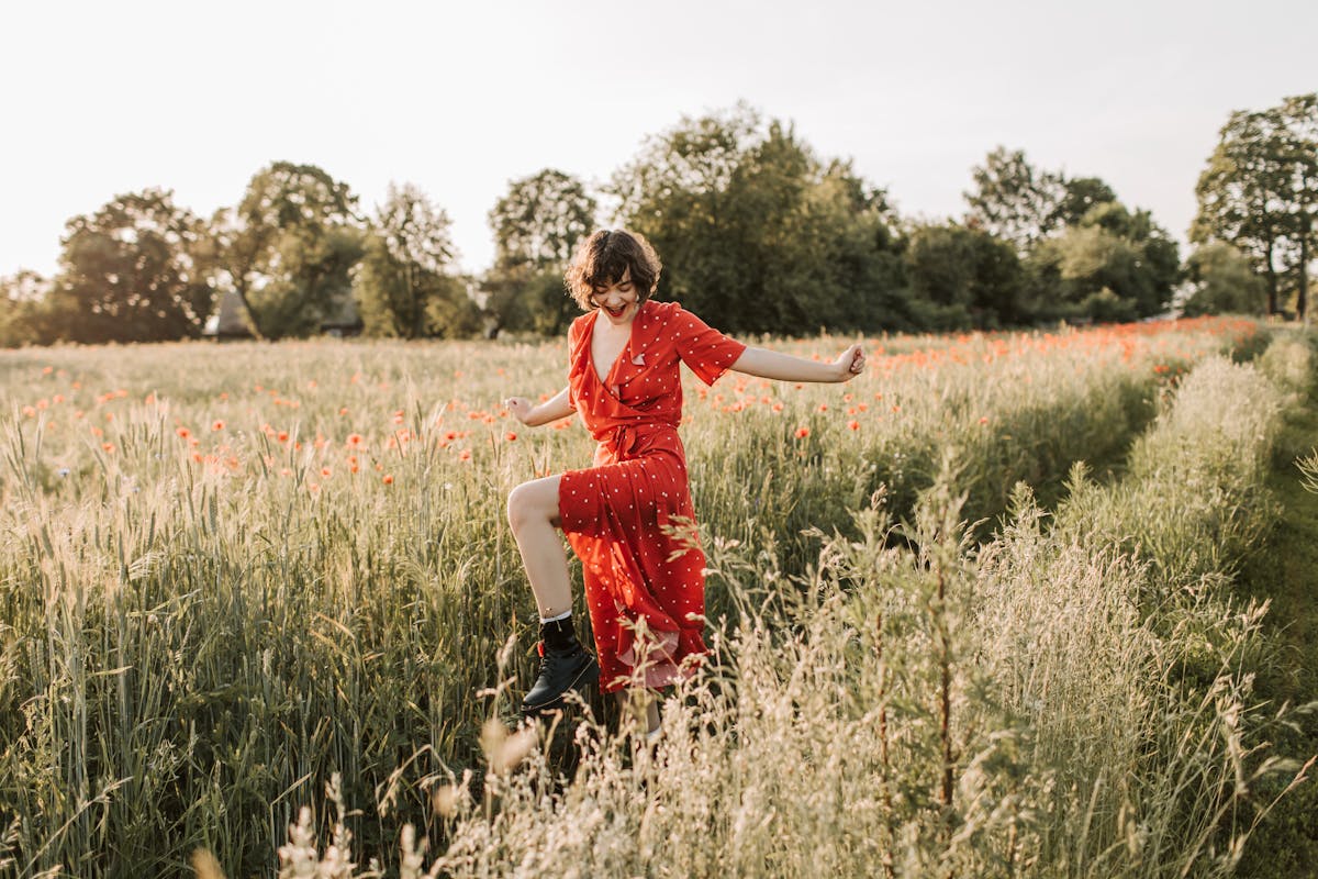 a woman in red dress walking on flower field