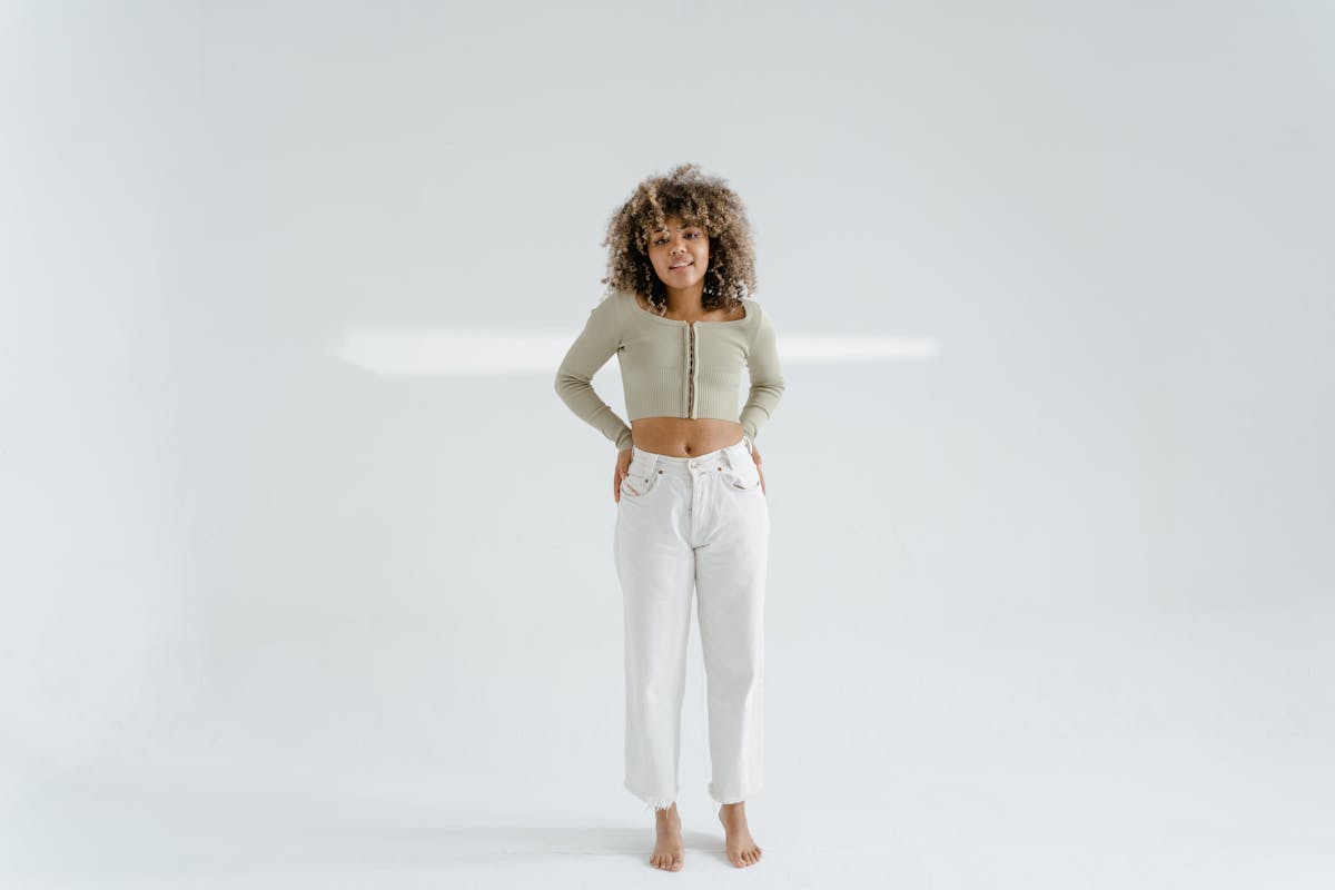an afro haired woman in beige crop top sleeves standing