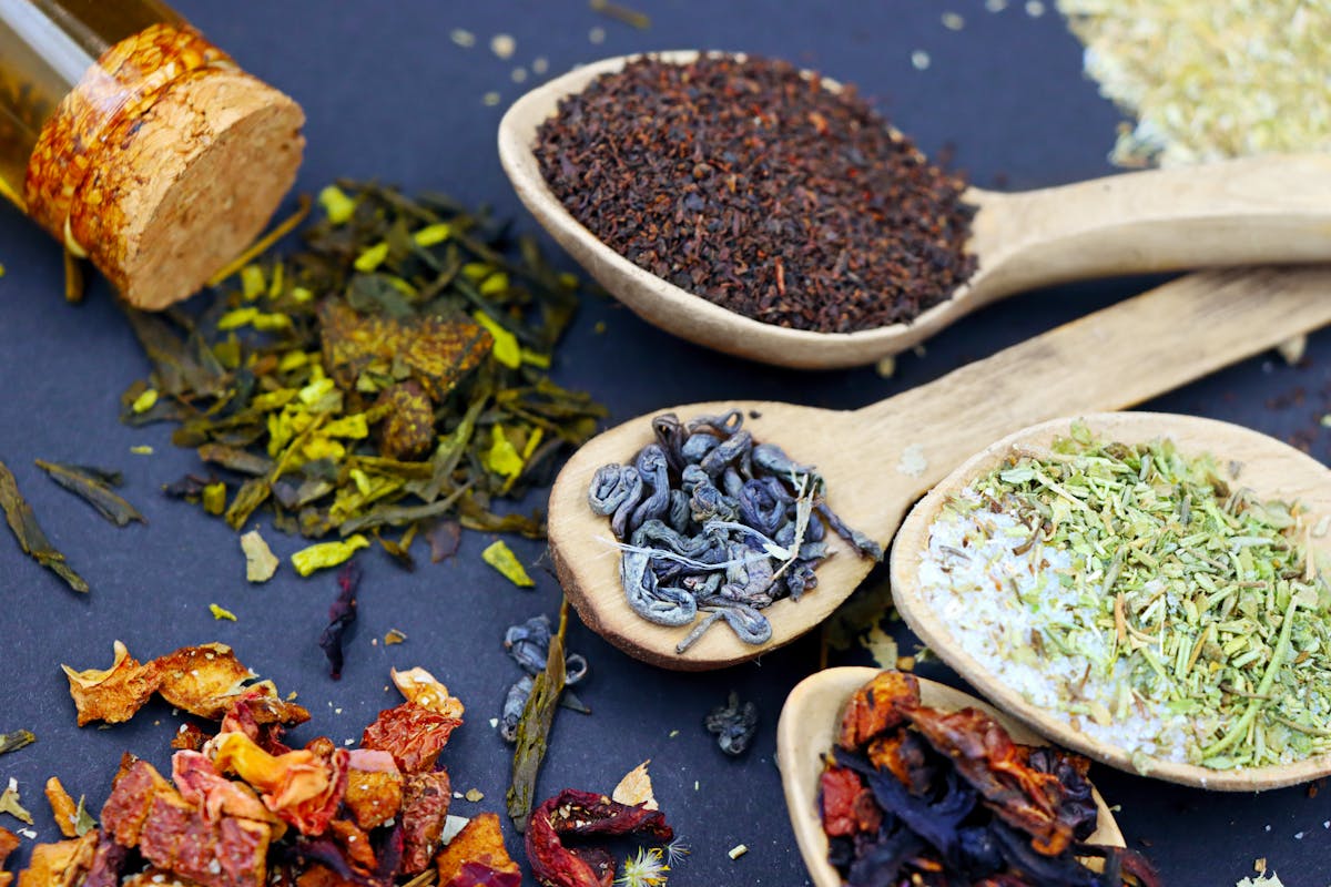 assorted loose leaf herbal teas with wooden spoons