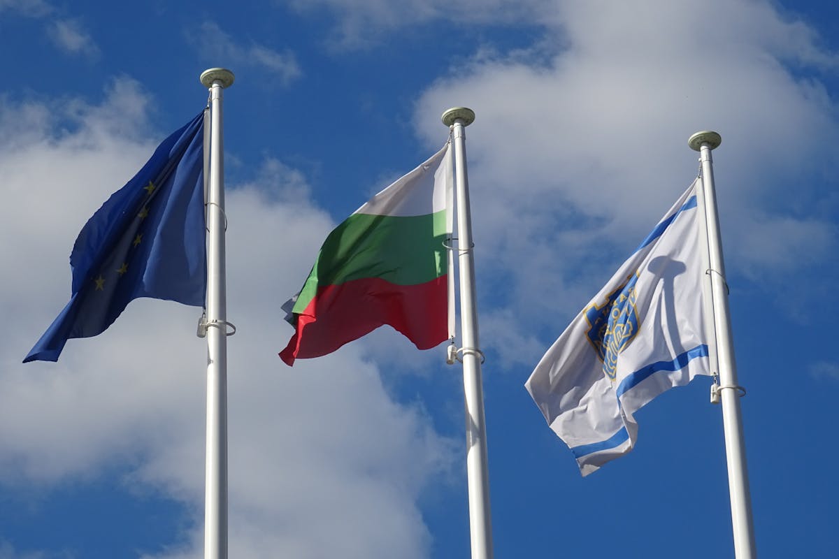 blue sky and white clouds over flags on poles