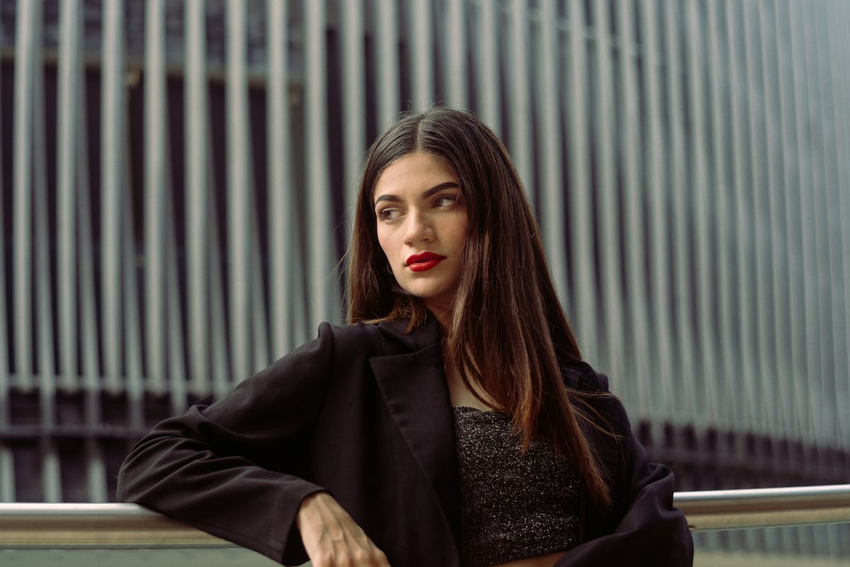 brunette woman posing in black blazer and sparkle bandeau top