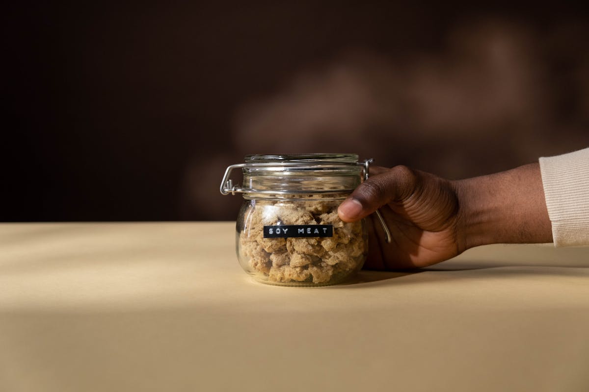 close up shot of a person holding a jar of soy meat