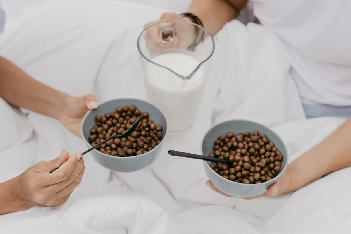 high angle shot of two people holding chocolate cereals and milk