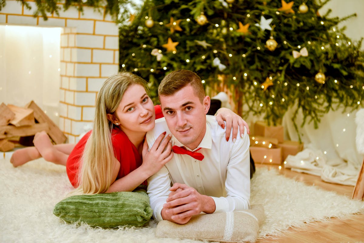 man and woman lying on rug near christmas tree