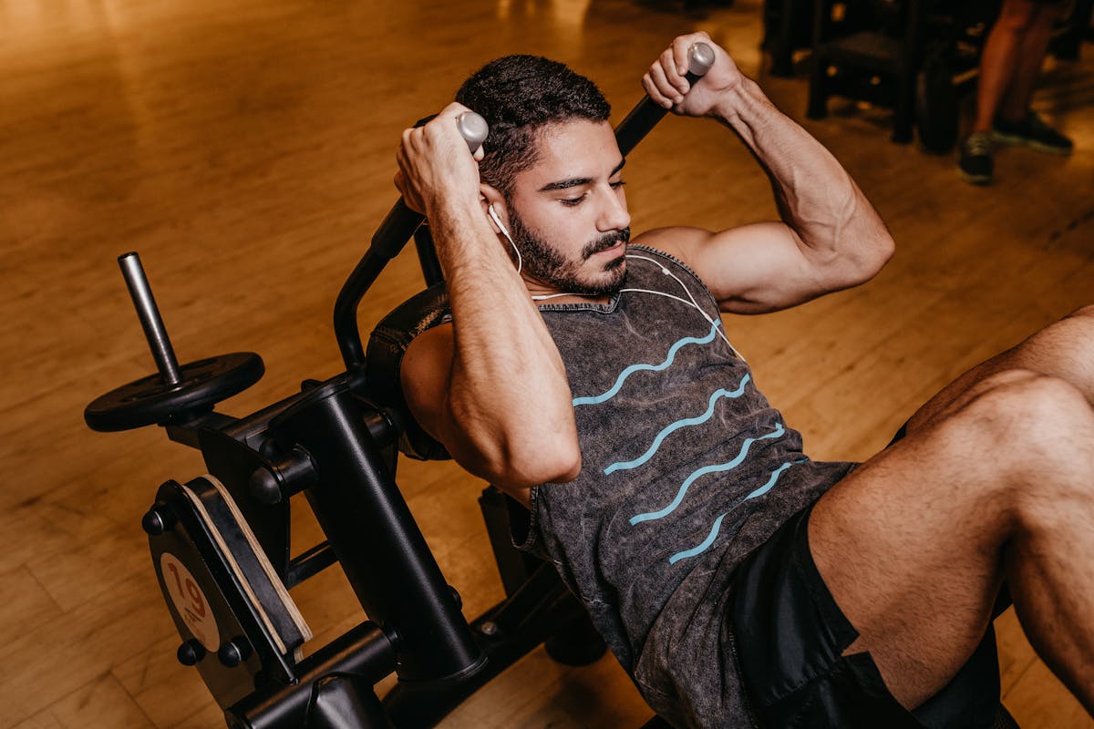 man in black and white tank top sitting on black exercise equipment