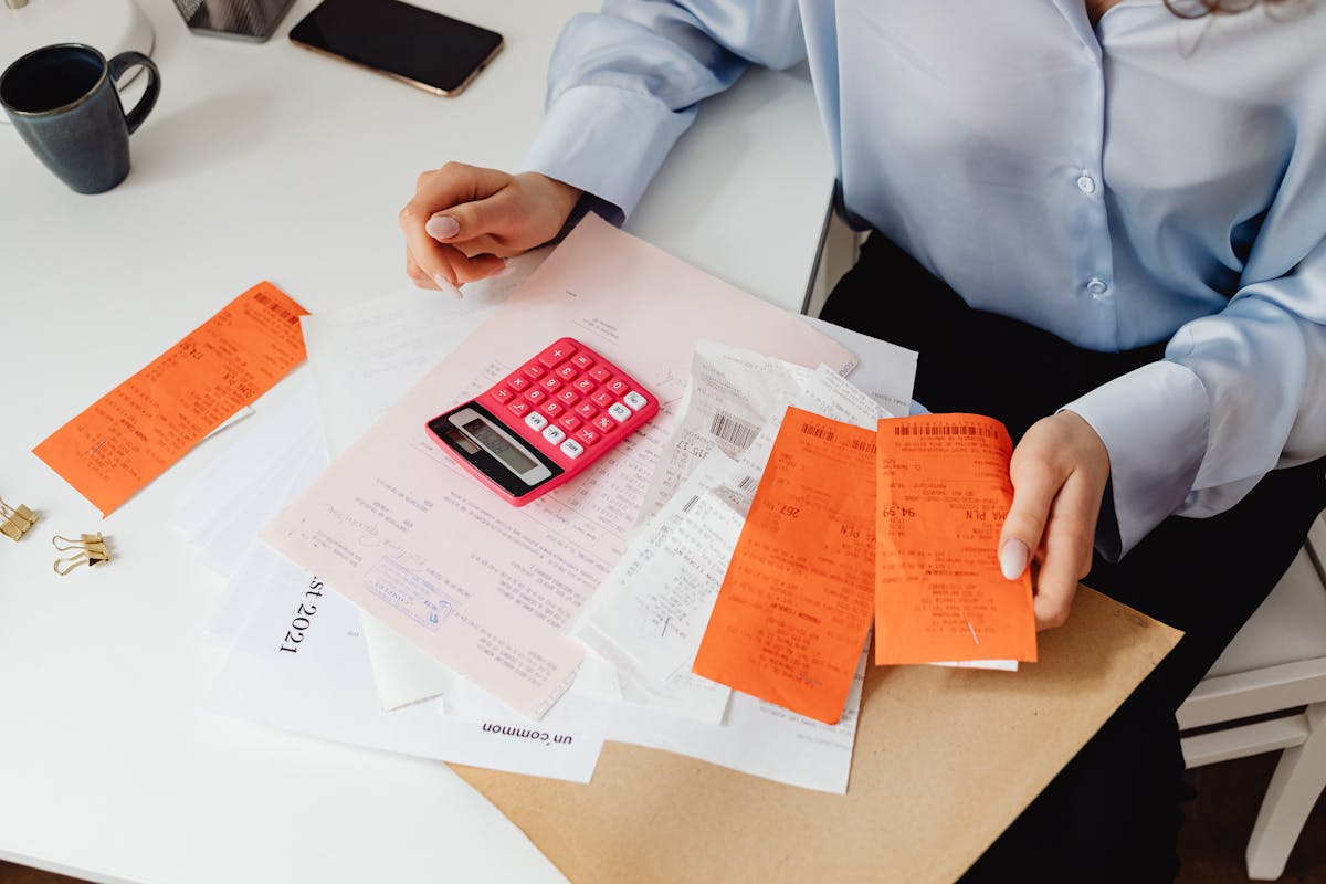 person holding receipts and using a calculator