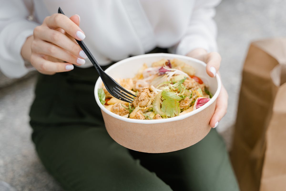 person holding white ceramic bowl with stainless steel fork