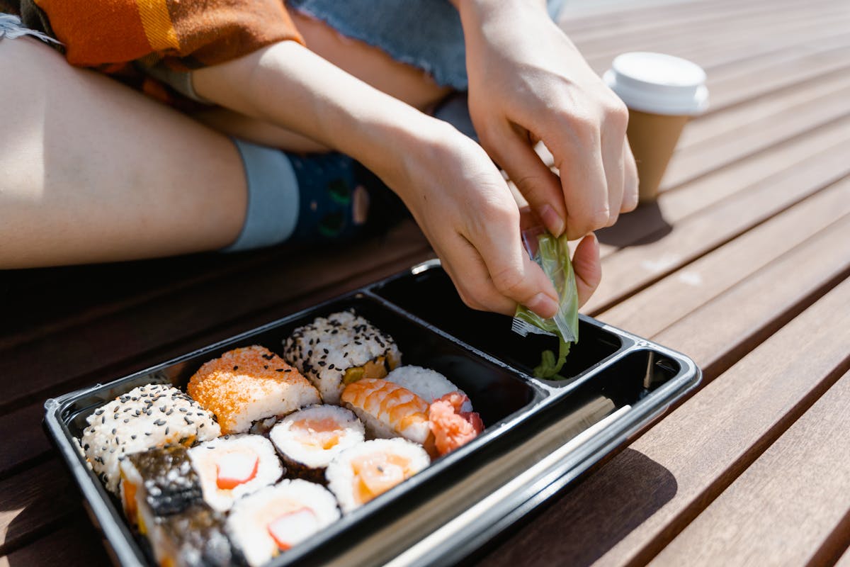 person putting a pack of sauce on the tray