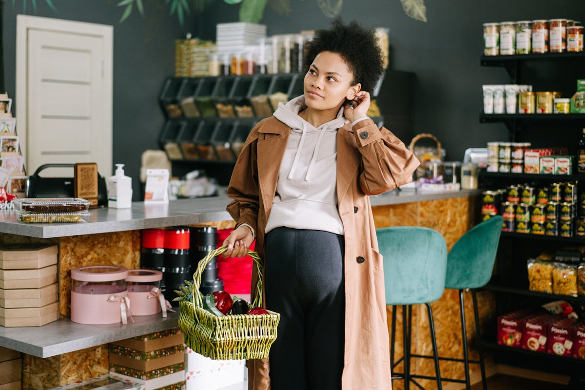 pregnant woman in brown coat holding basket in grocery store