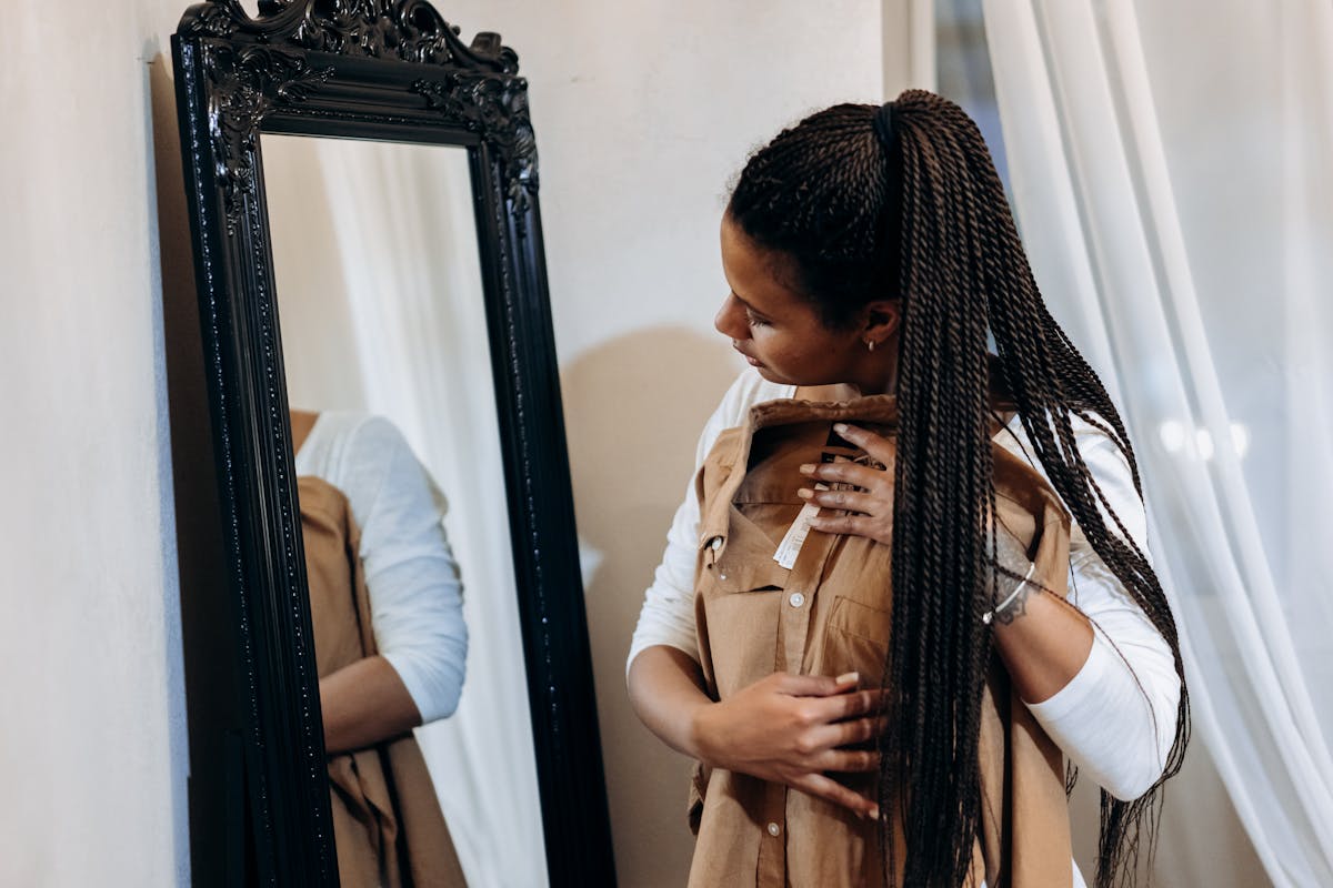 woman holding a dress looking at a mirror