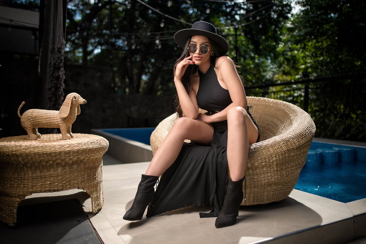 woman in black dress sitting by swimming pool woman in black dress sitting by swimming pool