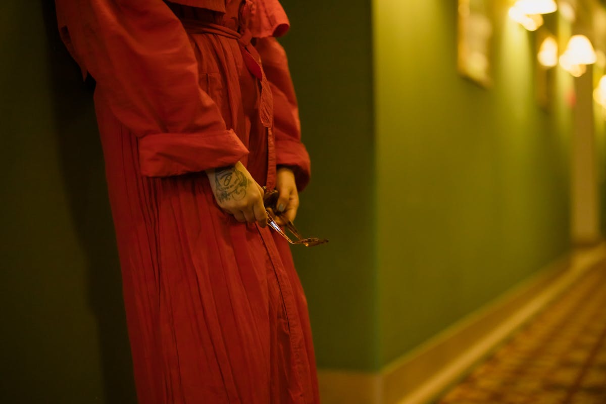 woman in red dress leaning on the wall
