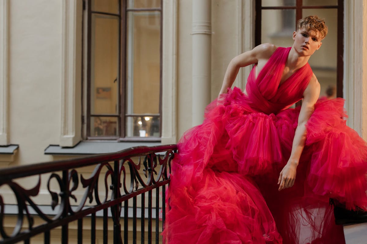 woman in red dress sitting on black metal fence