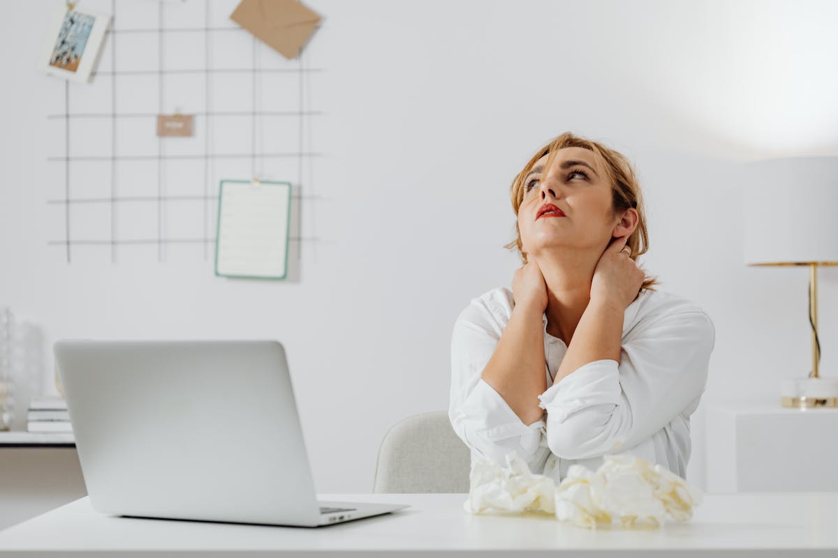 woman in white long sleeve shirt sitting at a table looking up woman in white long sleeve shirt sitting at a table looking up