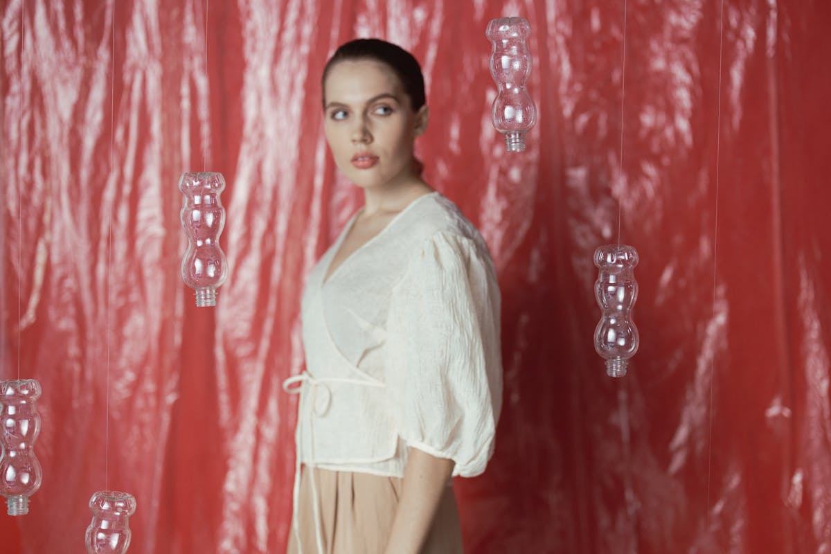 woman in white long sleeve shirt standing besides hanging plastic bottles