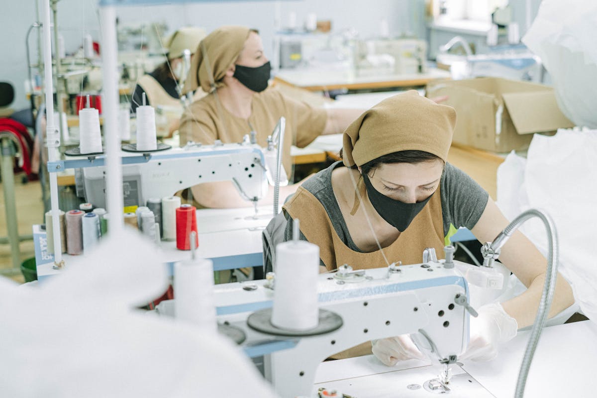 women in brown bandanas and apron working in a sewing factory