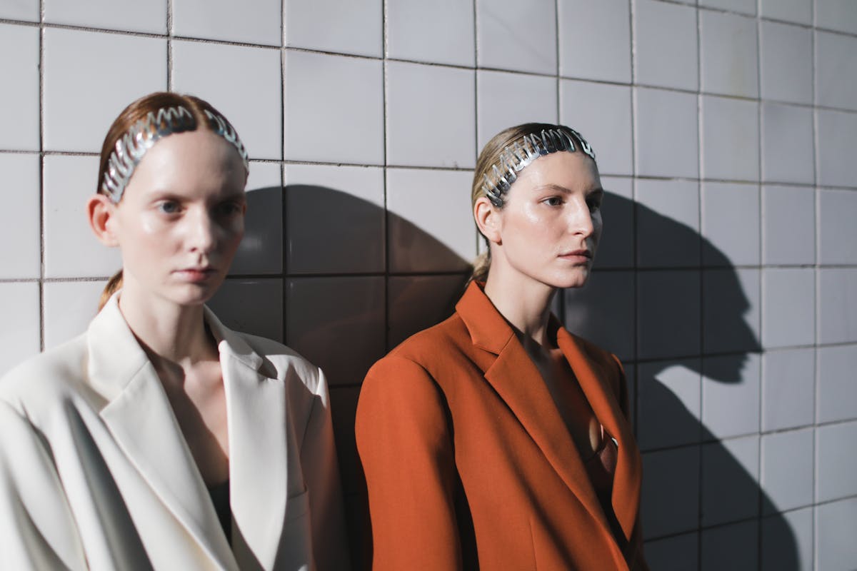 young women wearing suits posing against a wall with white tiles